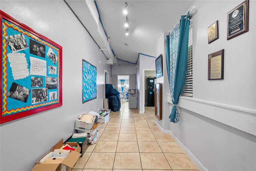 This photo showcases a versatile space with potential for various uses. The long hallway, lined with bulletin boards and storage areas, could serve as a welcoming entryway, a functional workspace, or even a creative display area. Its neutral color scheme and ample natural light create a bright and adaptable environment.