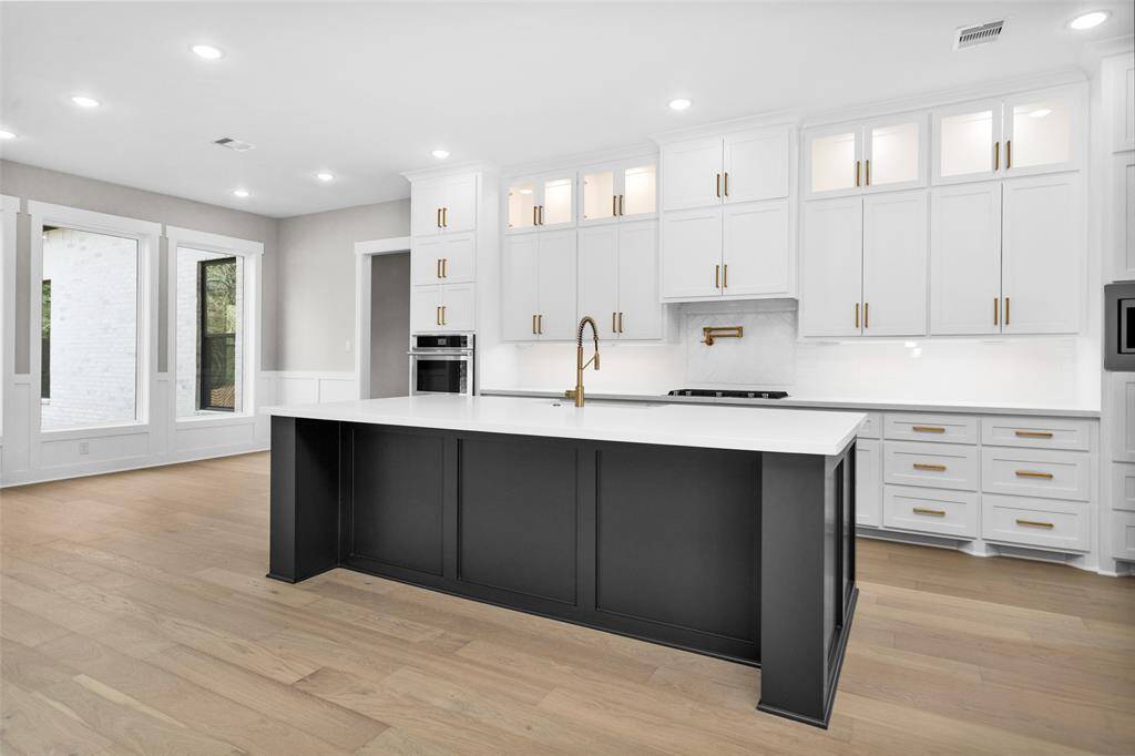 A stunning gourmet kitchen with quartz countertops, a large center island, stainless steel appliances, and custom cabinetry