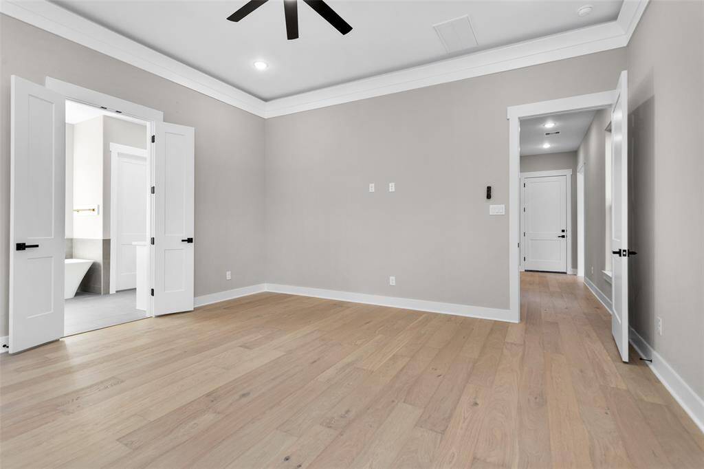A large primary bedroom with tray ceilings, neutral walls, and multiple windows that flood the space with natural light.