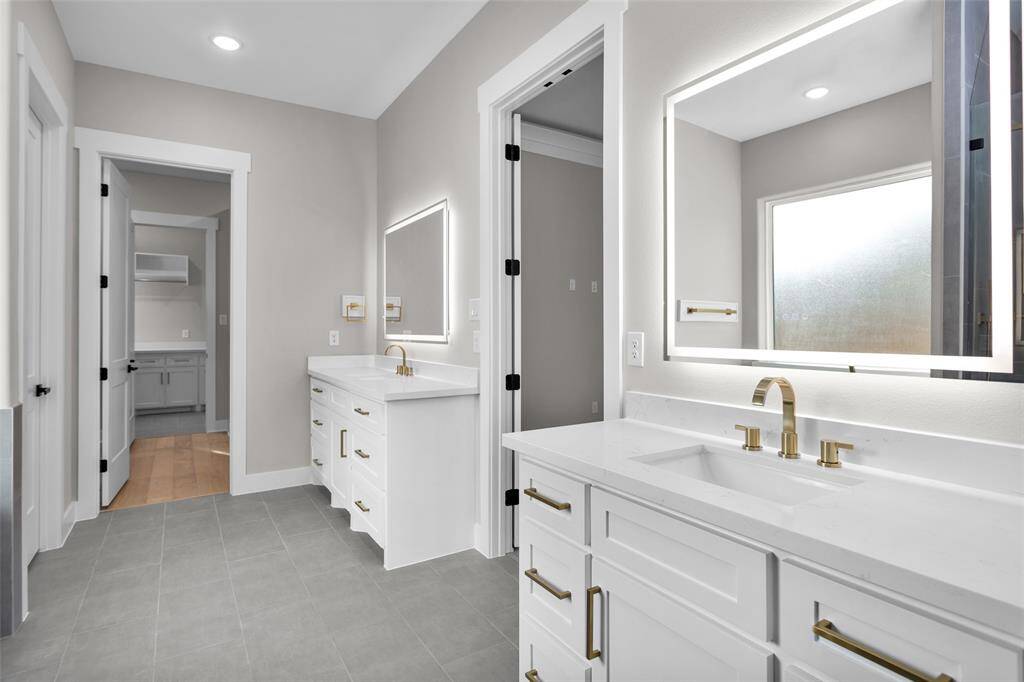 A luxurious ensuite bathroom featuring a soaking tub, walk-in shower, dual vanities, and a spacious walk-in closet with built-in shelving.