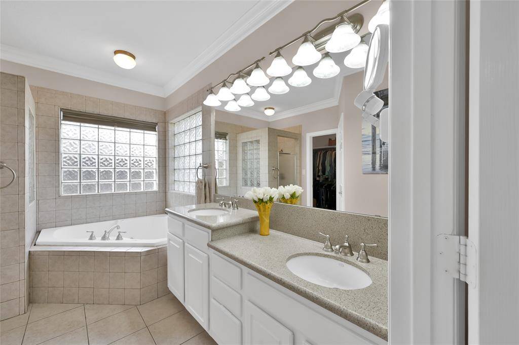 A soaking tub and separate shower provide options for relaxation in the primary bath. A large walk-in closet is nearby with additional built in cabinets. A separate water closet is also to the left.