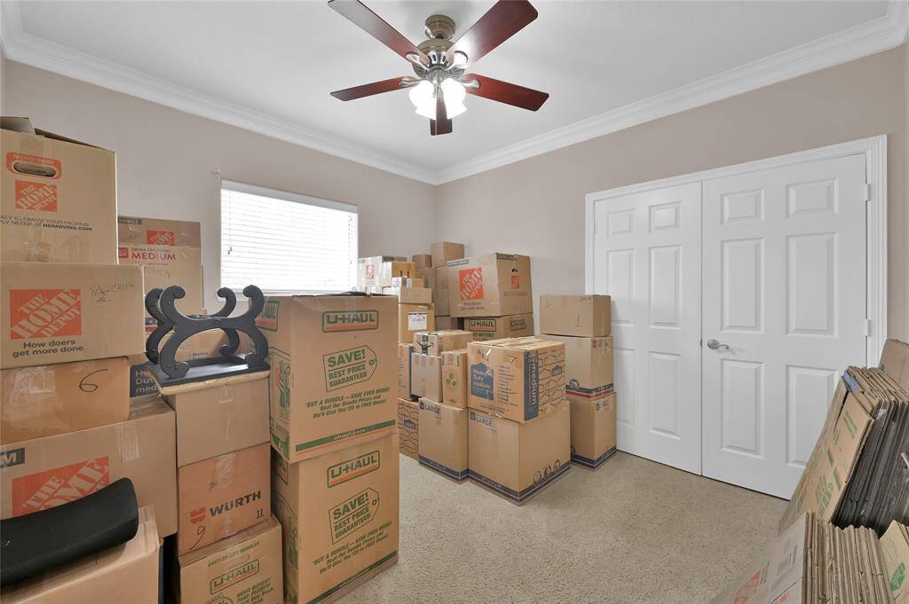 Another secondary bedroom that looks out to the front yard. Both secondary rooms have crown molding and ceiling fans.
