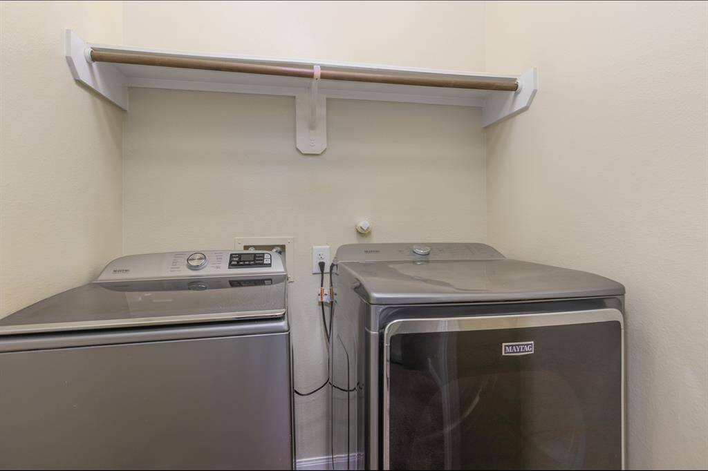 This photo shows a compact laundry area with a modern washer and dryer set, featuring a shelf above for additional storage.