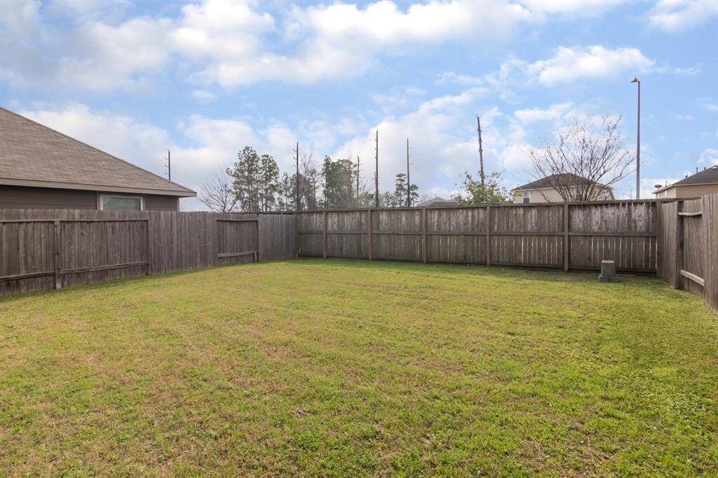Spacious fenced backyard with a well-maintained lawn, offering privacy and ample space for outdoor activities.