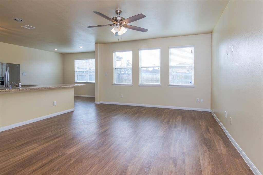 This home showcases a spacious, open-concept living area with wood flooring, neutral walls, and ample natural light from multiple windows.