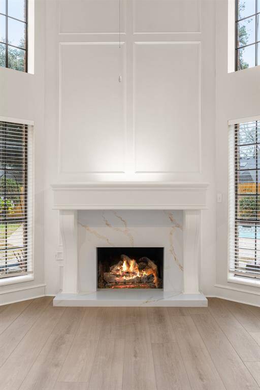 A stunning wooden mantle serves as the focal point, adding charm and character to this inviting space. Oversized windows flood the room with natural light, highlighting the exquisite crown molding and detailed craftsmanship.
