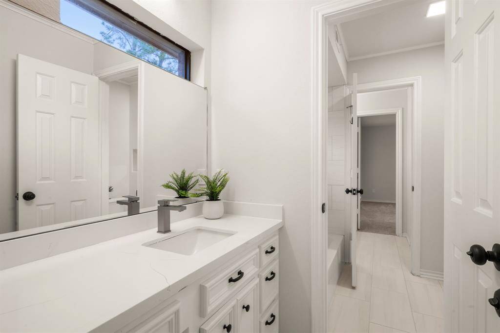 The Jack-and-Jill bathroom boasts quartz countertops, a double vanity, and built-in shelving in the shower/tub combo.