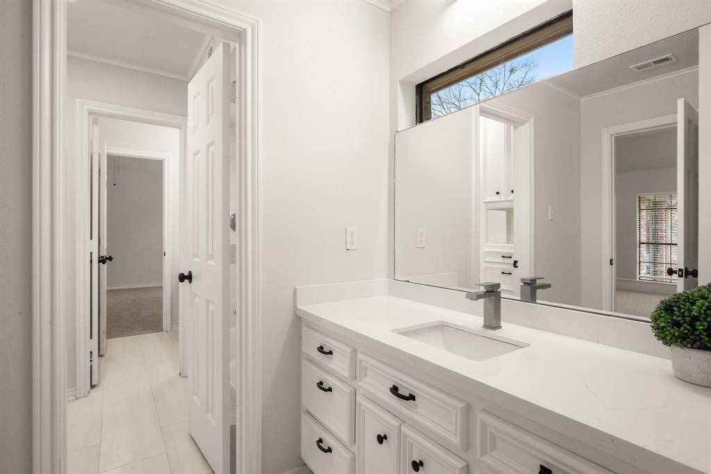 The Jack-and-Jill bathroom boasts quartz countertops, a double vanity, and built-in shelving in the shower/tub combo.
