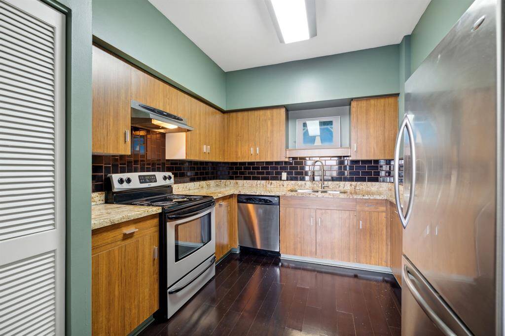 Kitchen with granite counters, stainless appliances and subway tiled backsplash.