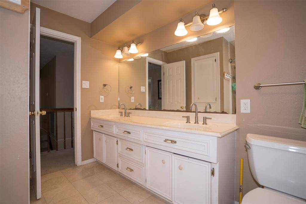 A view of the second bathroom, featuring dual sinks and a large vanity mirror, offering both style and functionality.