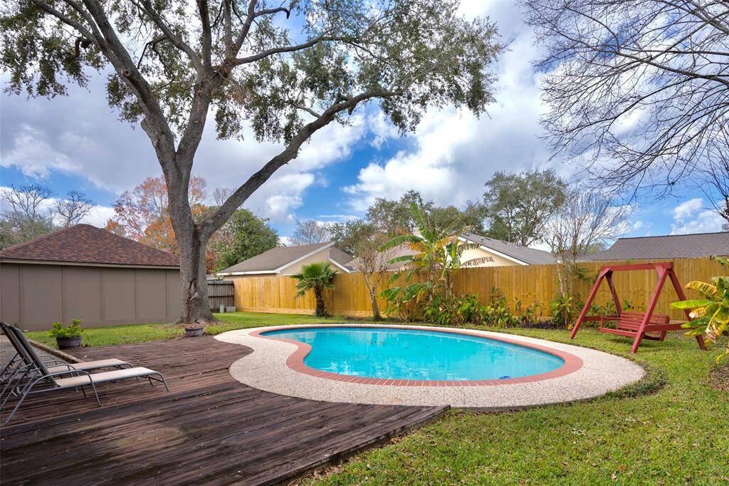 The private pool in the backyard is perfect for relaxation, complemented by a wooden lounging deck, a swing, and a few plants and trees for a serene outdoor retreat.