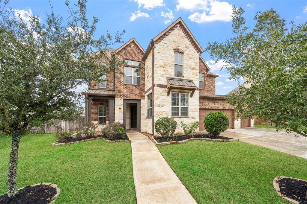This Stately two-story home has a combination of brick and stone exterior, featuring a well-maintained front yard with mature trees and shrubs. It has a welcoming pathway leading to the entrance and a Three-car garage.
