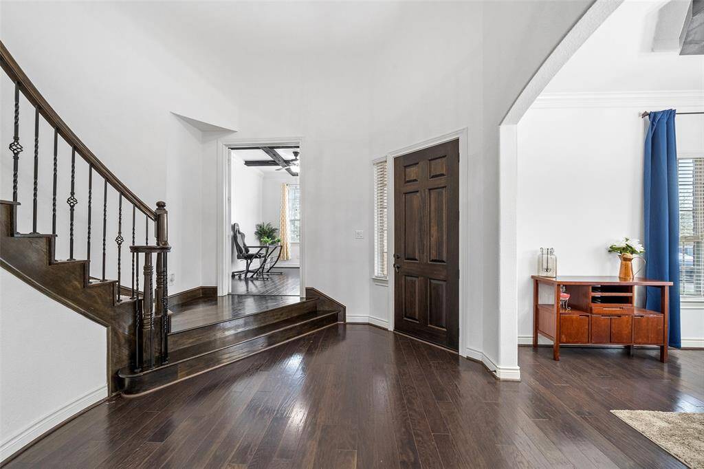 The welcoming entryway with rich dark hardwood floors and a stylish staircase is perfect for inviting your guest to your home. The cozy office is just up the landing with French doors.