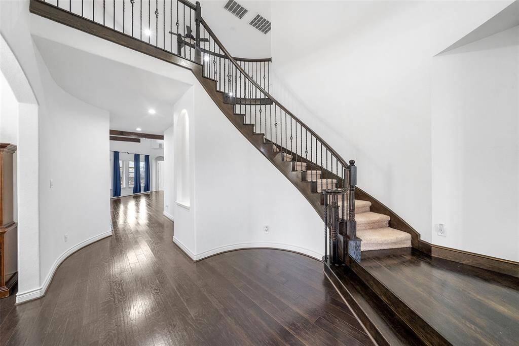 The sweeping staircase featuring wrought iron balusters is a custom touch for the entry.