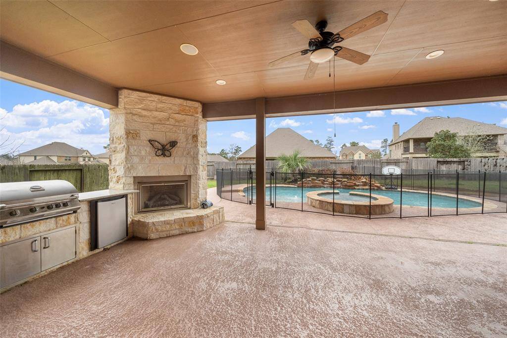 Just look at this spacious Summer Kitchen with a built-in grill, stone gas fireplace with ceramic logs that overlooks a fenced-in pool with a hot tub, providing a perfect outdoor entertainment area in a suburban backyard setting. NOTE: The pool around the fence can easily be removed.