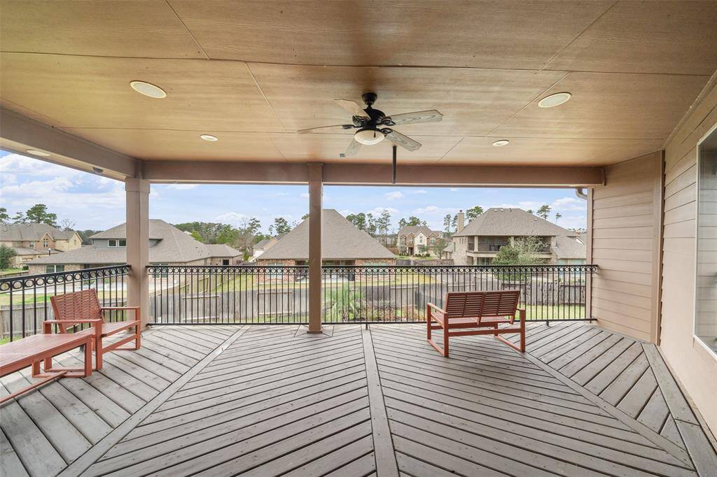 Spacious covered patio with ceiling fan, offering scenic views of a landscaped neighborhood.  Enjoy the views of the Lake from the Balcony.   Features comfortable seating and a stylish railing, perfect for relaxing or entertaining.
