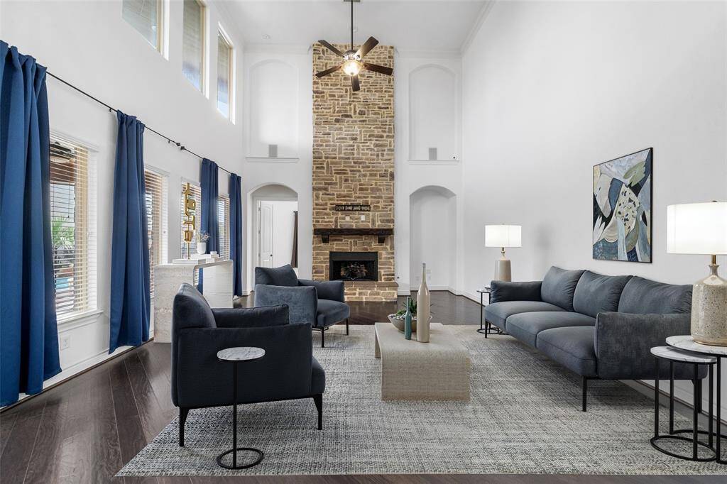 Another view of the large Living area featuring a striking floor-to-ceiling brick fireplace that also has ceramic logs. Digitally staged.