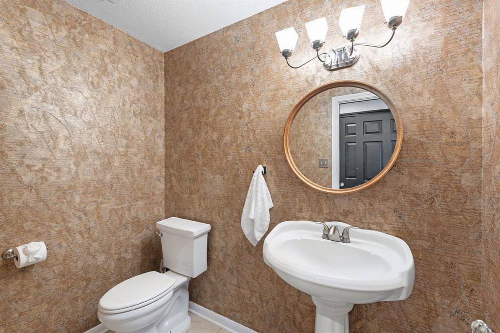 The large half-bathroom is located just off the entry as you take the short hall toward the primary suite.