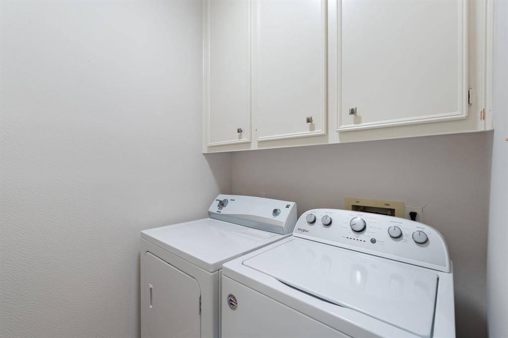 The laundry room has built-in cabinets to hide cleaning supplies.  Opposite the washer & dryer is additional storage and a folding table.