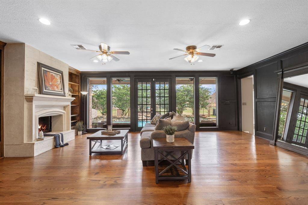 A close up of the family room shows how spacious this home is with dual ceiling fans, stone faced fireplace, decorative woodwork and much more.
