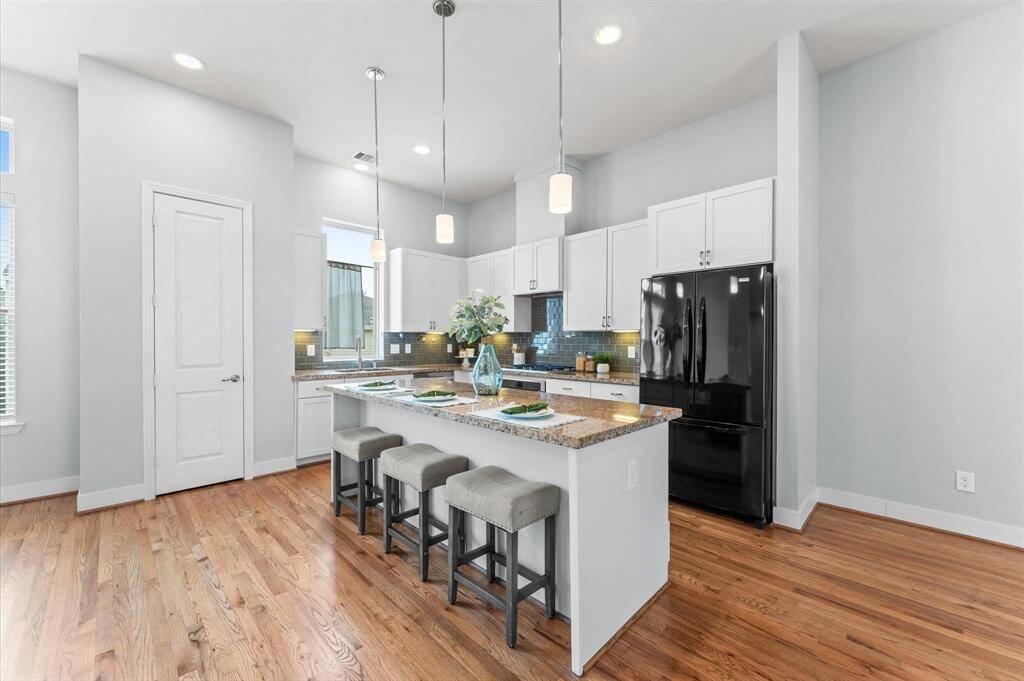 A chef’s dream, the kitchen is beautifully designed with a wide island featuring a granite countertop and stylish pendant lighting.