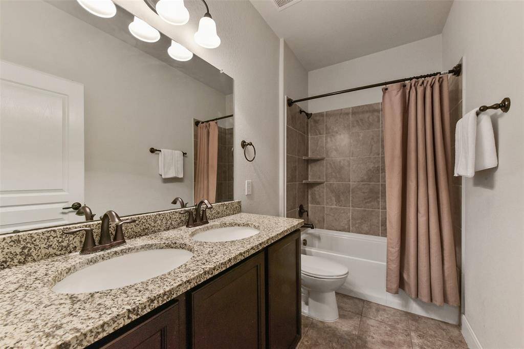 Secondary bathroom with double sink granite vanity.