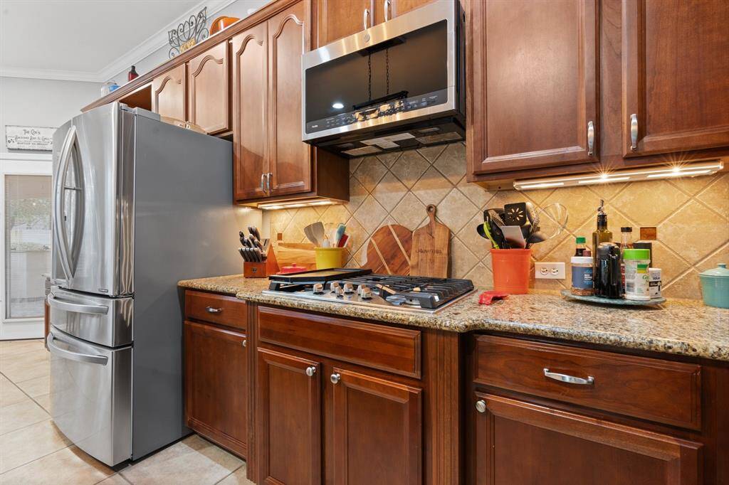 Modern kitchen with stainless steel appliances and built-in microwave. It features wood cabinetry, granite countertops, and under-cabinet lighting.