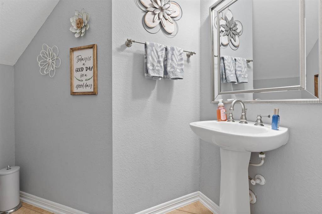 This is a modern, half bathroom featuring a pedestal sink and a large, decorative mirror. The room has a clean, bright feel.