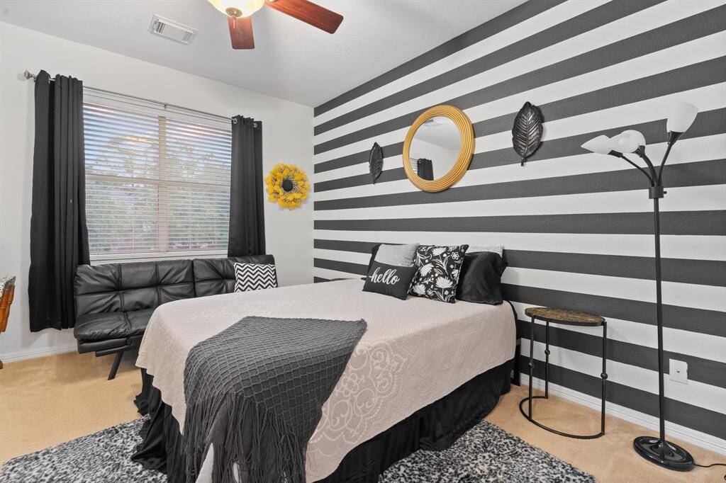 This bedroom features a modern design with a black and white striped wall. Natural light fills the room through a large window.