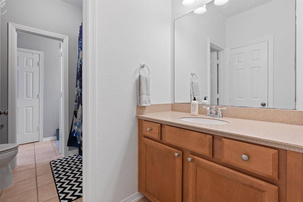 This bathroom features a sleek, neutral design with a large mirror above a wooden vanity and a modern countertop.