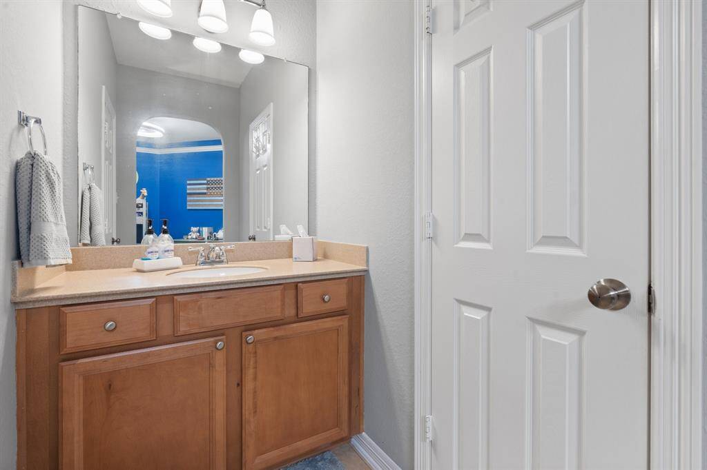 This bathroom has a wooden vanity, a large mirror, and ample lighting. The neutral walls complement the clean design.