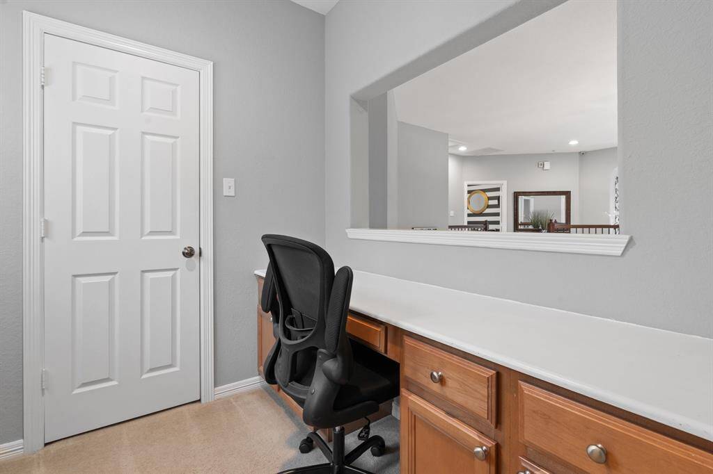 This room features a connecting home office nook with a built-in desk featuring wooden cabinets.