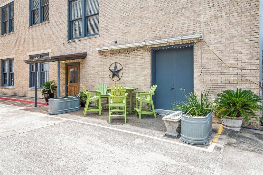 This photo shows a cozy outdoor seating area with green chairs, decorative plants in containers, and the welcoming main entrance. Not pictured are the two dedicated parking spots for 2A, only a few steps away.