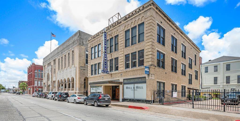 The photo depicts a three-story building in an urban setting with a mix of classical and commercial architectural styles.