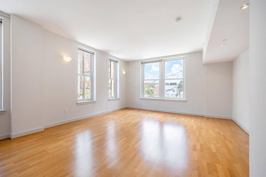This is a bright, airy room with hardwood floors, multiple windows for natural light, and a clean, neutral color scheme ideal for personal customization.