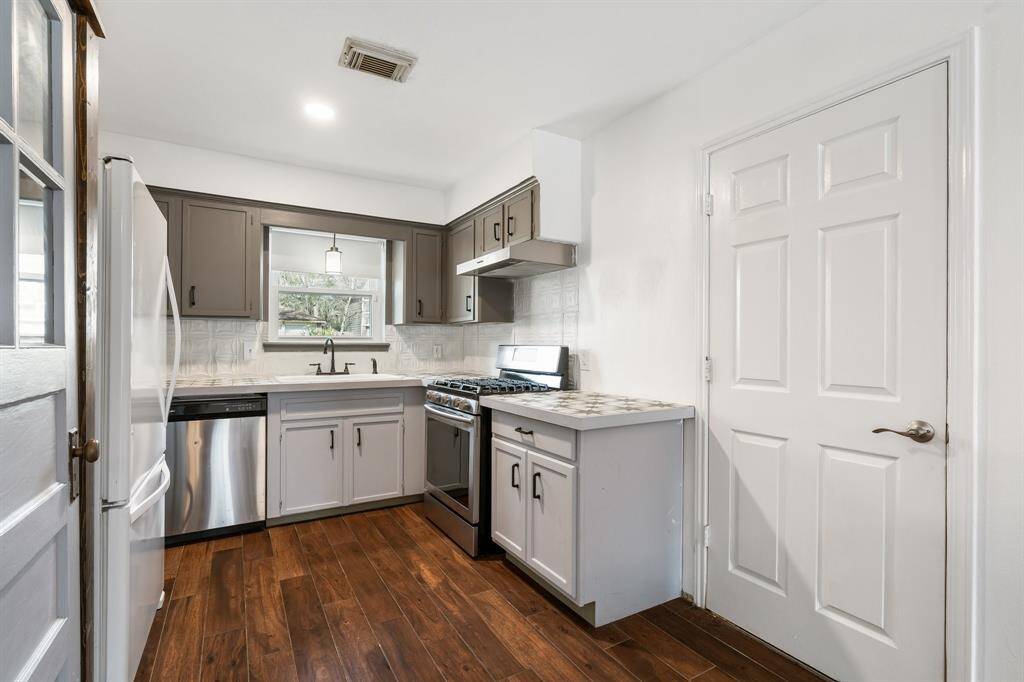This kitchen features a modern design with two-tone cabinetry, stainless steel range, and elegant tile flooring. The space is well-lit and includes a window above the sink for natural light.