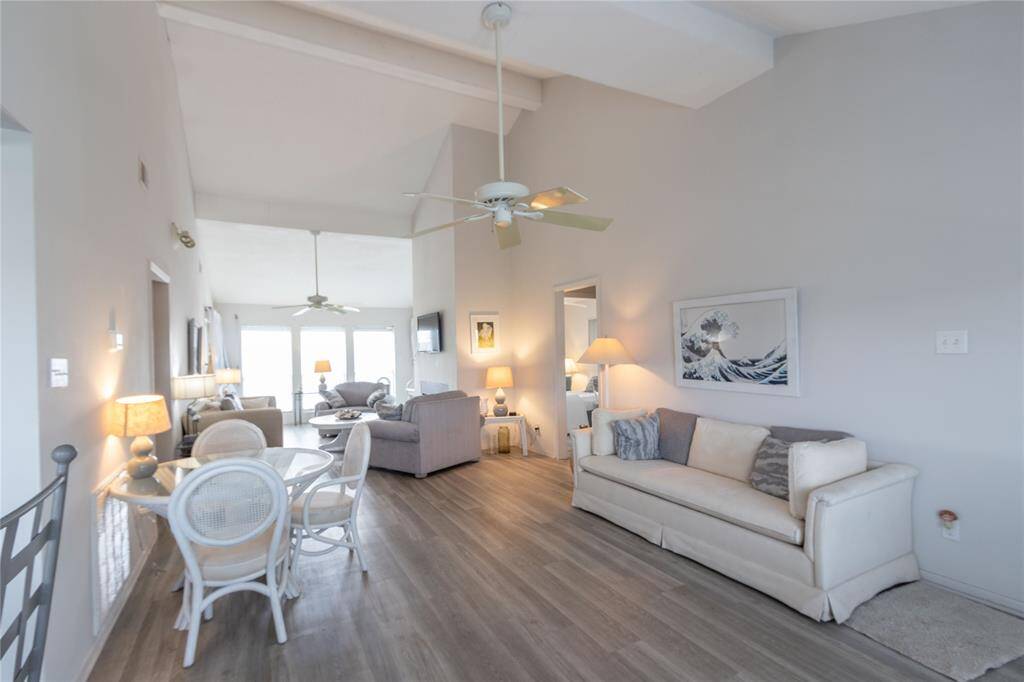 This photo showcases a bright, open living space with high ceilings and a neutral color palette. It features a cozy seating area, a dining table, and large windows that let in plenty of natural light. The room is modern and welcoming, perfect for comfortable living.