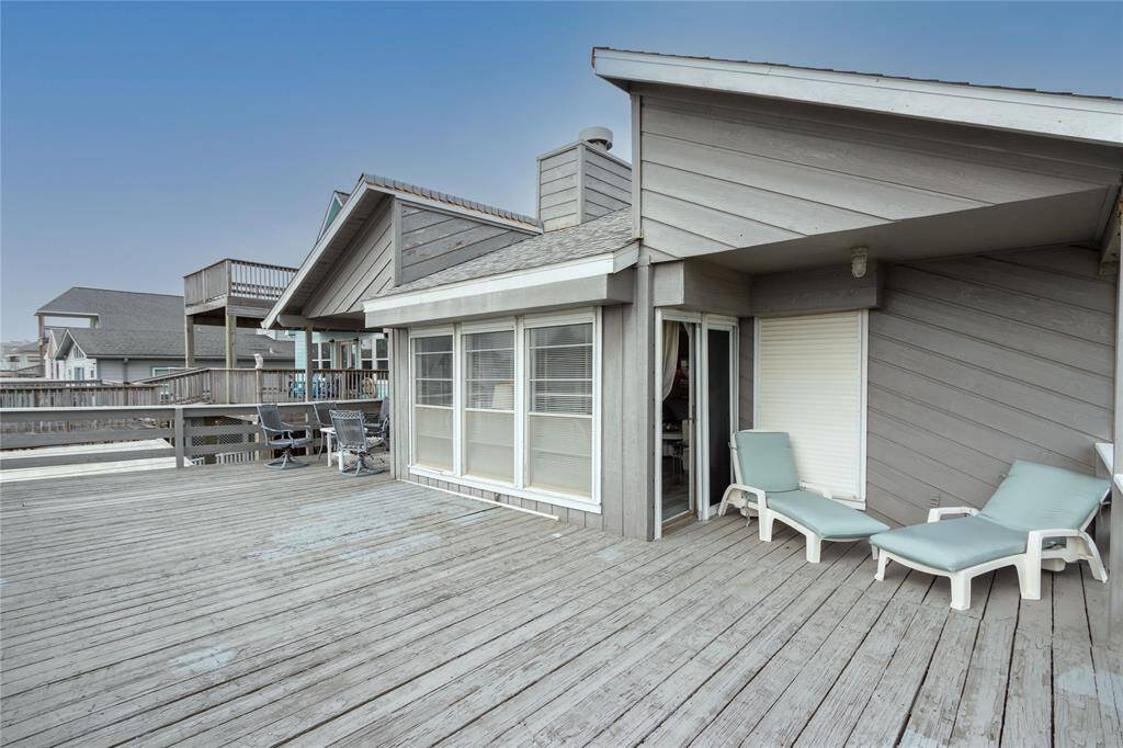 This home features a spacious wooden deck offering ample outdoor living space, with lounge chairs perfect for relaxing. The exterior has a modern, coastal design with large windows for natural light, creating an inviting atmosphere ideal for buyers seeking a canal/bayview retreat. Partially covered deck
