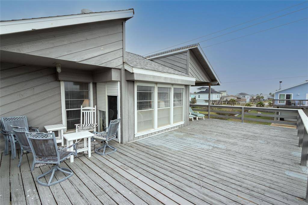 This photo showcases a spacious wooden deck attached to a house, featuring outdoor seating and surrounding views of a residential neighborhood. Ideal for relaxing or entertaining.partially covered deck.