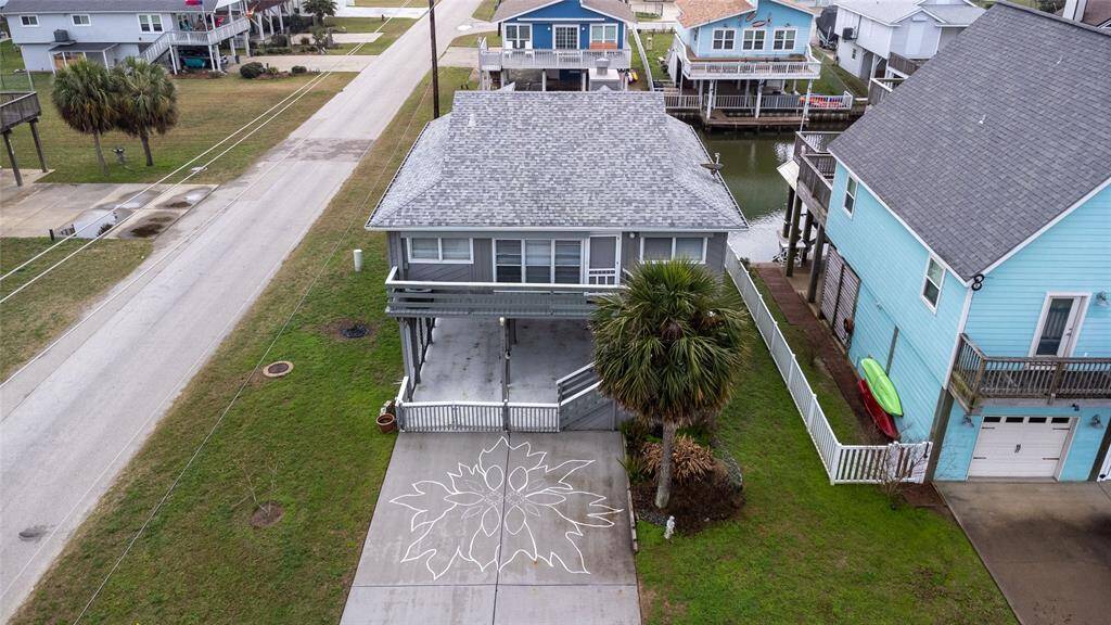 Charming coastal/canal home with a covered driveway and a decorative concrete design. Features a spacious front porch, surrounded by well-maintained landscaping, and is located near a canal. Perfect for waterfront living.