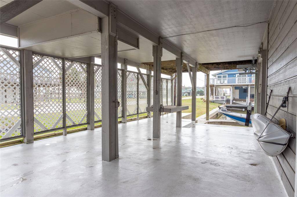This photo shows a covered outdoor space with a concrete floor, featuring lattice walls for partial enclosure. It overlooks a canal, with a boat docked nearby, and offers a view of neighboring homes, making it ideal for waterfront living and recreation.  Boat not included.