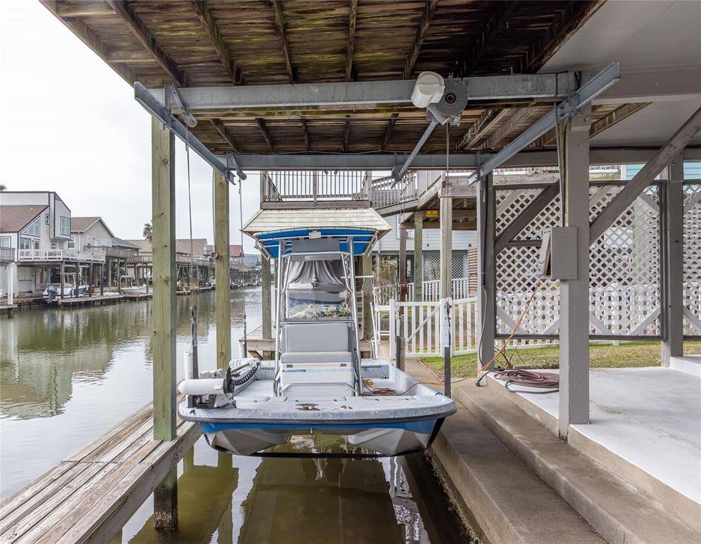This photo shows a waterfront property with a NEW private boat lift and dock (2024), ideal for boating enthusiasts. The area features a covered structure and is situated along a peaceful canal, providing easy water access and scenic views of neighboring homes. Boat not included.