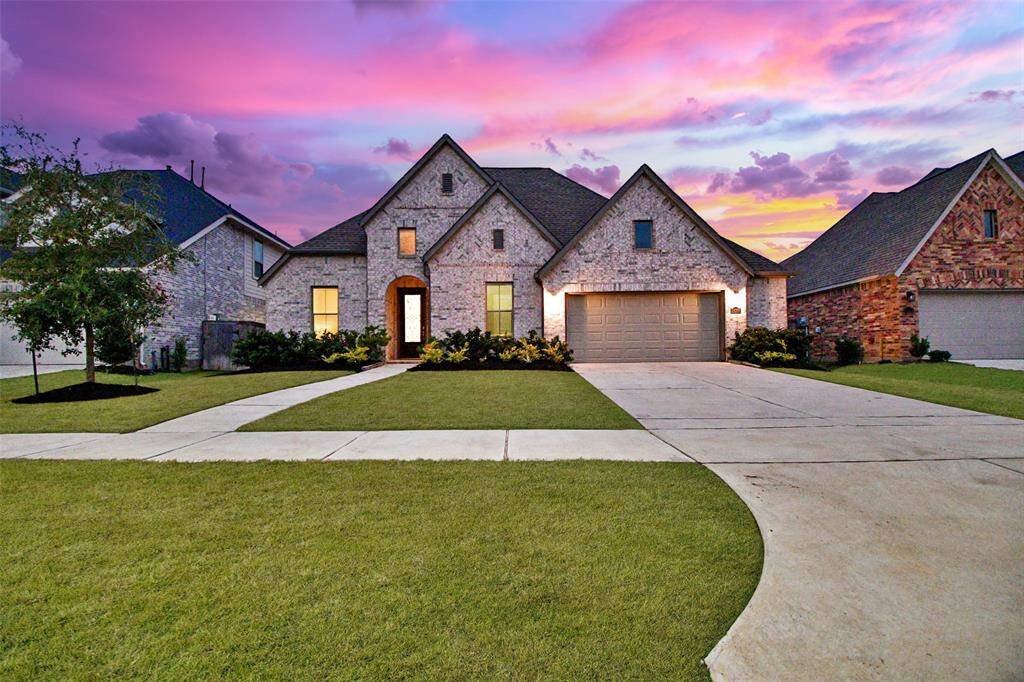 This stunning home by Coventry Homes features a gorgeous brick facade, a spacious two-car garage, and a beautifully maintained front yard.