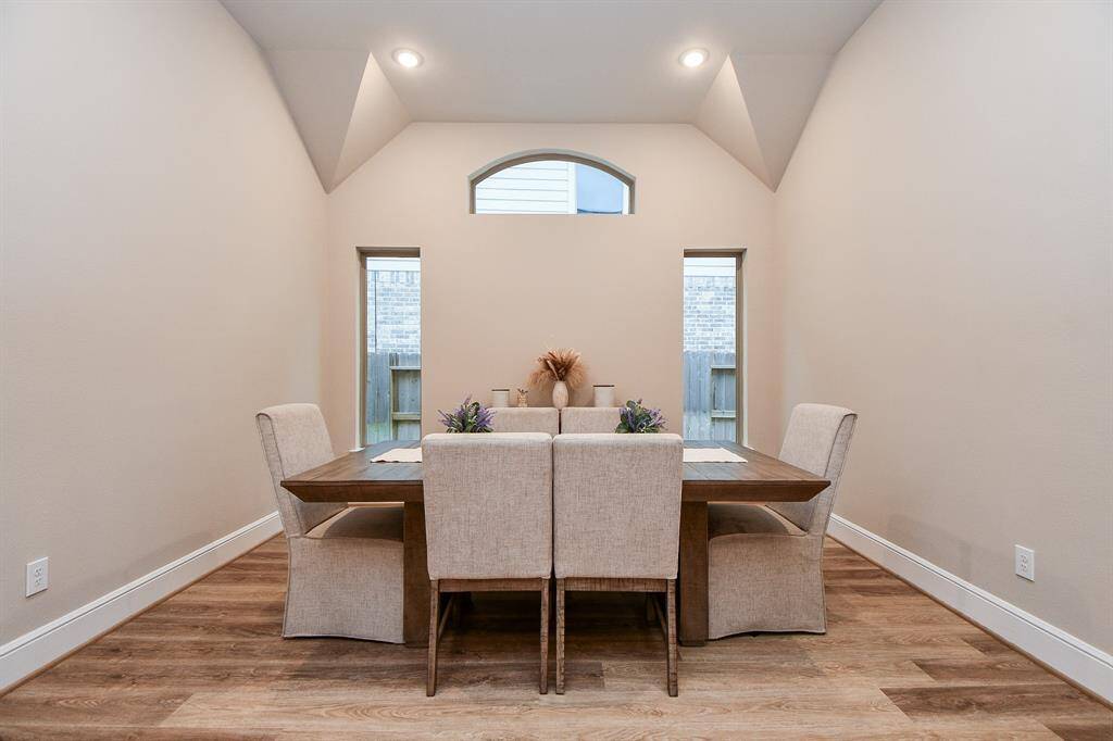 This showcases a chic dining room with high ceilings and ample natural light.