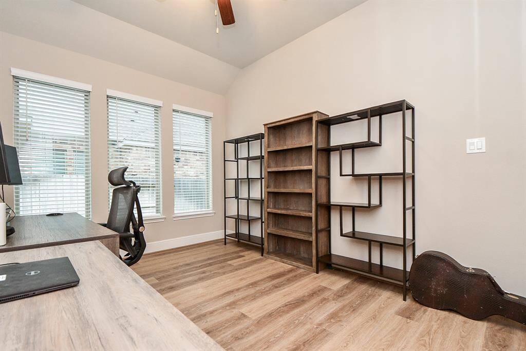 This bright home office features large windows with blinds, allowing plenty of natural light, creating a functional and inviting workspace.