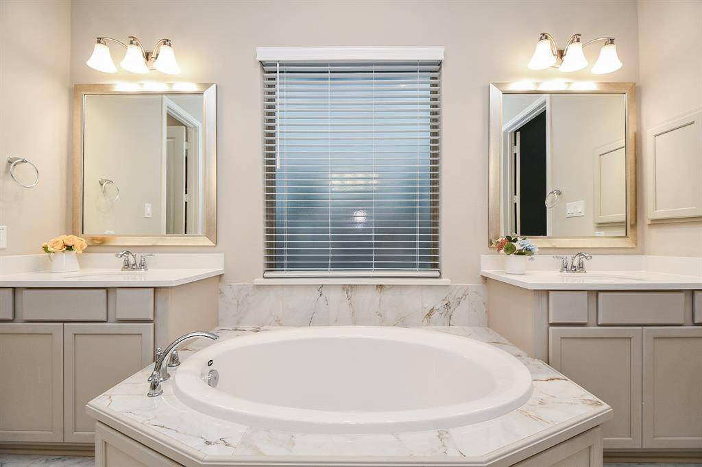 Side by side dual vanities in between a luxurious soaking tub.