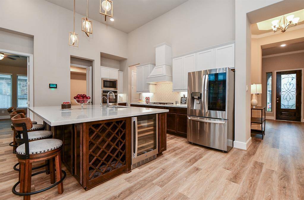 This modern kitchen features a huge island with seating, stainless steel appliances, and ample cabinetry. The open layout and elegant lighting create a warm, inviting atmosphere.