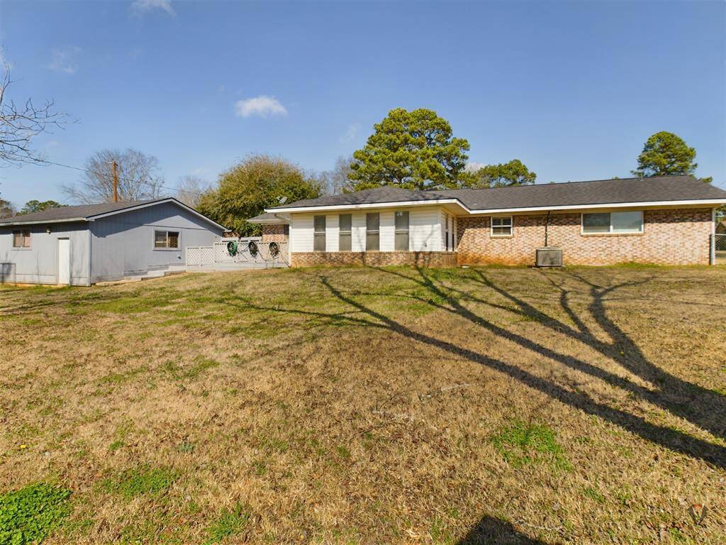 The yard is grassy with a few trees, offering ample outdoor space.