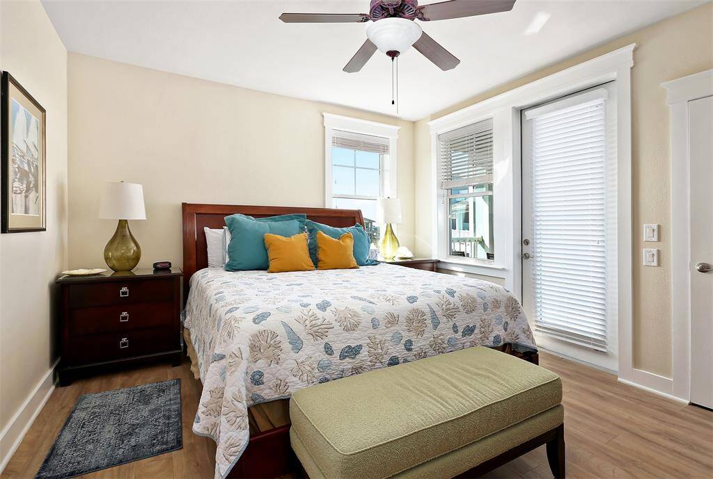 Wake up to natural light streaming through scattered windows in this serene bedroom, featuring private balcony access and calming coastal hues.
