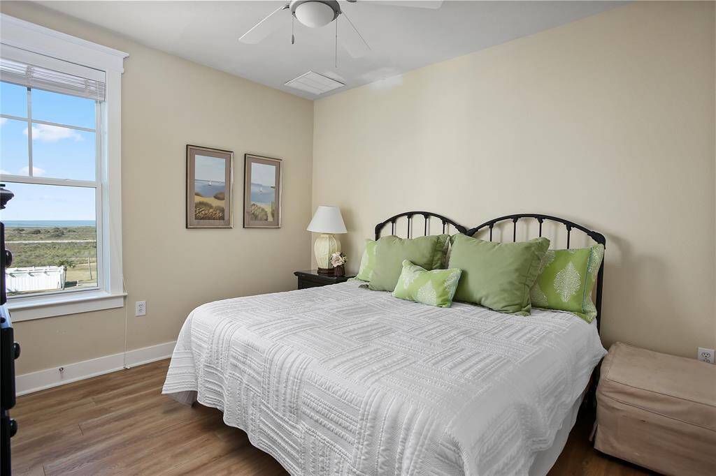 This peaceful third bedroom features a large window with Gulf views, soft neutral tones, and a ceiling fan for year-round comfort.